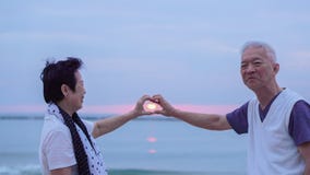 Asian senior couple together at sunrise beach. New year, new cha Stock Images Asian senior couple together at sunrise beach. New year, new cha Stock Images
