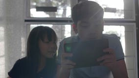 Asian sister and brother using a digital tablet together . stock footage Asian sister and brother using a digital tablet together . stock footage