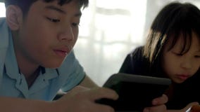 Asian sister and brother using a digital tablet together . stock footage Asian sister and brother using a digital tablet together . stock footage