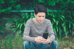 Asian man sitting and using smartphone stock images Asian man sitting and using smartphone stock images