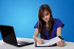 Asian student girl writing on notebook, on blue background stock photos Asian student girl writing on notebook, on blue background stock photos