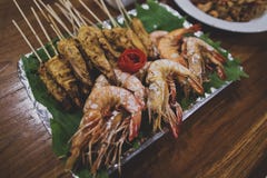 Asian Thai snacks are located on a plate standing on a wooden table. There are shashliks on skewers, fried shrimps and vegetables. royalty free stock photography Asian Thai snacks are located on a plate standing on a wooden table. There are shashliks on skewers, fried shrimps and vegetables. royalty free stock photography