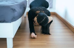 Asian woman bent and searching something under bed lost thing