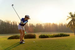 Asian woman golf player doing golf swing tee off on the green sunset evening time, she presumably does exercise. royalty free stock images Asian woman golf player doing golf swing tee off on the green sunset evening time, she presumably does exercise. royalty free stock images