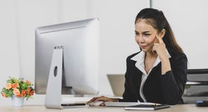 Asian woman office people sitting at working desk and using computer while serious to think as intend at office place