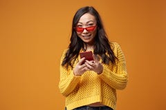 Asian woman in red glasses with phone in her hand looking at camera
