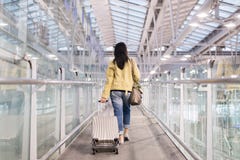 Asian Woman Traveler Dragging Carry On Luggage Suitcase At Airport Corridor Walking To Departure Gates Royalty Free Stock Photography