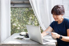 Asian young woman holding credit card and using laptop computer while sitting in cafe. Online shopping concept. Copy space. royalty free stock photos Asian young woman holding credit card and using laptop computer while sitting in cafe. Online shopping concept. Copy space. royalty free stock photos