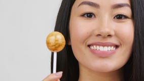 Asian Young Woman Holding Lollipop Candy Posing Over White Background