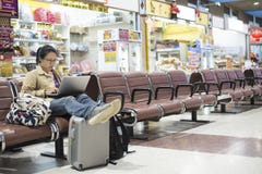Asiatinjugendlicher, der Smartphone an Flughafenabfertigungsgebäude sittin verwendet lizenzfreies stockfoto Asiatinjugendlicher, der Smartphone an Flughafenabfertigungsgebäude sittin verwendet lizenzfreies stockfoto