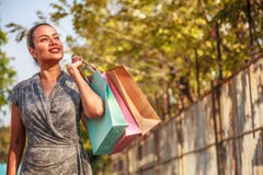 Asiatinkäufer ist kaufend halten und die bunten Einkaufstaschen, die seitlich auf dem links- und Kopienraum auf dem Recht schauen Lizenzfreies Stockbild Asiatinkäufer ist kaufend halten und die bunten Einkaufstaschen, die seitlich auf dem links- und Kopienraum auf dem Recht schauen Lizenzfreies Stockbild