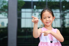 Asiatische Lage des kleinen M?dchens, die dazu ihren Zeigefinger mit nettem L?cheln zeigt lizenzfreie stockfotografie Asiatische Lage des kleinen M?dchens, die dazu ihren Zeigefinger mit nettem L?cheln zeigt lizenzfreie stockfotografie