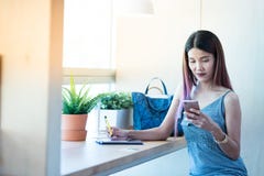 Asiatischer Damengebrauch und -gespräch im intelligenten Handy beim Sitzen in c stockbilder Asiatischer Damengebrauch und -gespräch im intelligenten Handy beim Sitzen in c stockbilder
