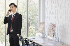 Asiatischer Gesch?ftsmann, der Mobiltelefon im B?ro verwendet lizenzfreie stockbilder Asiatischer Gesch?ftsmann, der Mobiltelefon im B?ro verwendet lizenzfreie stockbilder