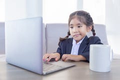 Asiatisches Kind im Geschäftsgebrauchslaptop mit heißem ceremic Becher lizenzfreie stockfotografie Asiatisches Kind im Geschäftsgebrauchslaptop mit heißem ceremic Becher lizenzfreie stockfotografie