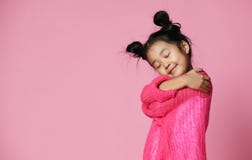 Asiatisches Kindermädchen mit geschlossenen Augen in der rosa Strickjackenumarmung und Traum lizenzfreie stockbilder Asiatisches Kindermädchen mit geschlossenen Augen in der rosa Strickjackenumarmung und Traum lizenzfreie stockbilder