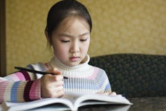 Asiatisches Mädchen, das Heimarbeit tut lizenzfreies stockbild Asiatisches Mädchen, das Heimarbeit tut lizenzfreies stockbild