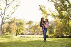 Asiatisk Caucasian kvinna som bär hennes unga dotter i en parkera royaltyfri fotografi Asiatisk Caucasian kvinna som bär hennes unga dotter i en parkera royaltyfri fotografi