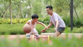 Asiatisk fader & son som spelar basket i trädgård i morgonen i ultrarapid stock video Asiatisk fader & son som spelar basket i trädgård i morgonen i ultrarapid stock video