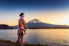 Asiatisk kvinna som bär den japanska traditionella kimonot på det Fuji berget Solnedgång på Kawaguchiko sjön i Japan arkivbild Asiatisk kvinna som bär den japanska traditionella kimonot på det Fuji berget Solnedgång på Kawaguchiko sjön i Japan arkivbild