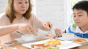 Asiatisk moder med sonen som hemma äter lunch lager videofilmer Asiatisk moder med sonen som hemma äter lunch lager videofilmer