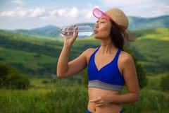 Asiatiskt förnyar kvinnadricksvatten för härliga unga sportar efter sommardag för het värme i berg royaltyfri bild Asiatiskt förnyar kvinnadricksvatten för härliga unga sportar efter sommardag för het värme i berg royaltyfri bild