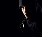 Assassin émotif, jeune et attirant dans les gants sur le fond noir image stock Assassin émotif, jeune et attirant dans les gants sur le fond noir image stock