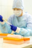 Assistant de laboratoire avec une pipette dans des ses mains pour l'essai de sang Flacons pour l'analyse de sang sur le support photographie stock libre de droits Assistant de laboratoire avec une pipette dans des ses mains pour l'essai de sang Flacons pour l'analyse de sang sur le support photographie stock libre de droits