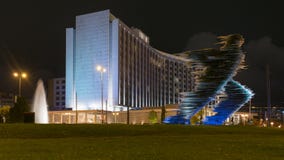 Atenas, Grécia 25 de novembro de 2015 Atenas na noite contra a estátua do corredor e uma construção moderna foto de stock Atenas, Grécia 25 de novembro de 2015 Atenas na noite contra a estátua do corredor e uma construção moderna foto de stock