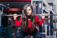 Athletic girl crouches with a barbell. beautiful woman doing physical exercises in the gym. sport fitness stock image Athletic girl crouches with a barbell. beautiful woman doing physical exercises in the gym. sport fitness stock image