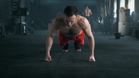 Atleta com um corpo bonito e um torso despido que fazem o exerc?cio de impulso-UPS no assoalho no gym 4K disparou em um tom escur video estoque Atleta com um corpo bonito e um torso despido que fazem o exerc?cio de impulso-UPS no assoalho no gym 4K disparou em um tom escur video estoque