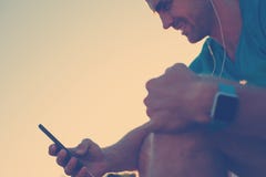 Atleta de sorriso com o smartphone e o relógio esperto que descansam após o exercício duro imagens de stock Atleta de sorriso com o smartphone e o relógio esperto que descansam após o exercício duro imagens de stock