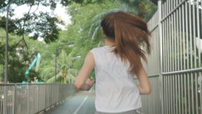 Atletische jonge Aziatische vrouw die en zich vóór training bij zonsopgang in een stadspark opwarmen uitrekken stock videobeelden Atletische jonge Aziatische vrouw die en zich vóór training bij zonsopgang in een stadspark opwarmen uitrekken stock videobeelden