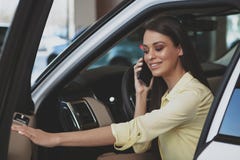 Atrakcyjna kobieta używa jej mądrze telefon podczas gdy bying nowego samochód zdjęcia royalty free Atrakcyjna kobieta używa jej mądrze telefon podczas gdy bying nowego samochód zdjęcia royalty free
