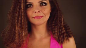 Atrakcyjna kobieta z kędzierzawym włosy i dymiącymi oczami w różowych bodysuit spojrzeniach przy kamerą i przystosowywa włosy zdjęcie wideo Atrakcyjna kobieta z kędzierzawym włosy i dymiącymi oczami w różowych bodysuit spojrzeniach przy kamerą i przystosowywa włosy zdjęcie wideo