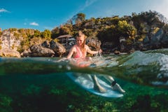Atrakcyjna surfingowiec dziewczyna z surfboard Surfingowiec siedzi przy deską w oceanie zdjęcie stock Atrakcyjna surfingowiec dziewczyna z surfboard Surfingowiec siedzi przy deską w oceanie zdjęcie stock