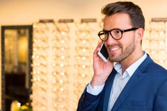 Atrakcyjny okulista używa telefon komórkowego w jego szkłach robi zakupy obrazy stock Atrakcyjny okulista używa telefon komórkowego w jego szkłach robi zakupy obrazy stock