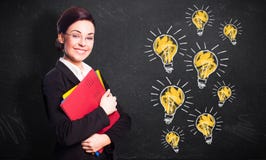 Atrakcyjny uśmiechnięty bizneswoman przed blackboard z wiele lightbulbs obraz royalty free Atrakcyjny uśmiechnięty bizneswoman przed blackboard z wiele lightbulbs obraz royalty free