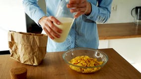 Att h?lla f?r ung kvinna mj?lkar in i en bunke av cornflakes i k?ket ultrarapidvideo stock video Att h?lla f?r ung kvinna mj?lkar in i en bunke av cornflakes i k?ket ultrarapidvideo stock video