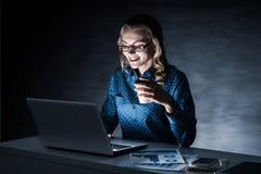 Attractive Blonde Working On Laptop In Dark Office. Mixed Media Stock Photo Attractive Blonde Working On Laptop In Dark Office. Mixed Media Stock Photo