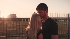 An attractive couple in love embrace and enjoy an intimate moment together, against the sunset or sunrise stock footage An attractive couple in love embrace and enjoy an intimate moment together, against the sunset or sunrise stock footage
