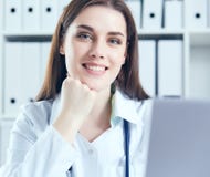 Attractive female doctor working on her laptop in her office. Happy doctor waiting for patient. royalty free stock photos Attractive female doctor working on her laptop in her office. Happy doctor waiting for patient. royalty free stock photos