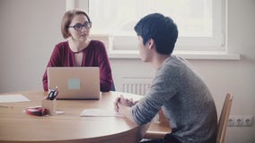 Attractive female leader listening to Japanese man at job interview. Lawyer woman consulting young handsome businessman. stock video Attractive female leader listening to Japanese man at job interview. Lawyer woman consulting young handsome businessman. stock video