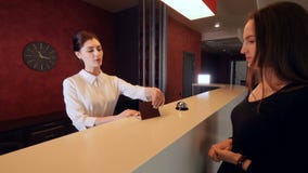 Attractive woman checking in hotel reception lobby. Travelling on vacation carrying luggage. stock footage Attractive woman checking in hotel reception lobby. Travelling on vacation carrying luggage. stock footage