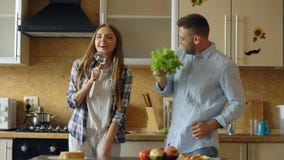 Attractive young joyful couple have fun dancing and singing while cooking in the kitchen at home stock photography Attractive young joyful couple have fun dancing and singing while cooking in the kitchen at home stock photography