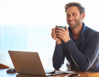 Attractive young man smiling while holding a coffee cup Royalty Free Stock Images Attractive young man smiling while holding a coffee cup Royalty Free Stock Images