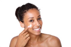 Attractive young woman applying cream on face