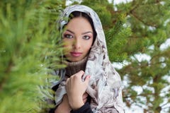 Attractive young woman with a scarf on her head in the winter forest near fir trees, snow falling royalty free stock photography Attractive young woman with a scarf on her head in the winter forest near fir trees, snow falling royalty free stock photography