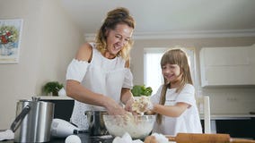 Attraktiv goda som ser modern, och hennes lilla dotter som försöker att göra ren deras händer från en deg, medan laga mat tillsam stock video Attraktiv goda som ser modern, och hennes lilla dotter som försöker att göra ren deras händer från en deg, medan laga mat tillsam stock video