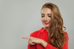 Attraktiv modell med makeup och långt lockigt hår som åt sidan pekar och ler på vit bakgrund fotografering för bildbyråer Attraktiv modell med makeup och långt lockigt hår som åt sidan pekar och ler på vit bakgrund fotografering för bildbyråer